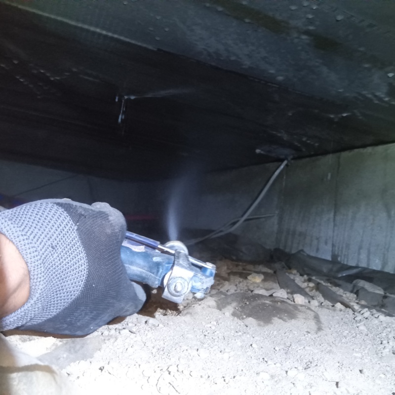 床下の土壌にシロアリ駆除剤を散布する様子