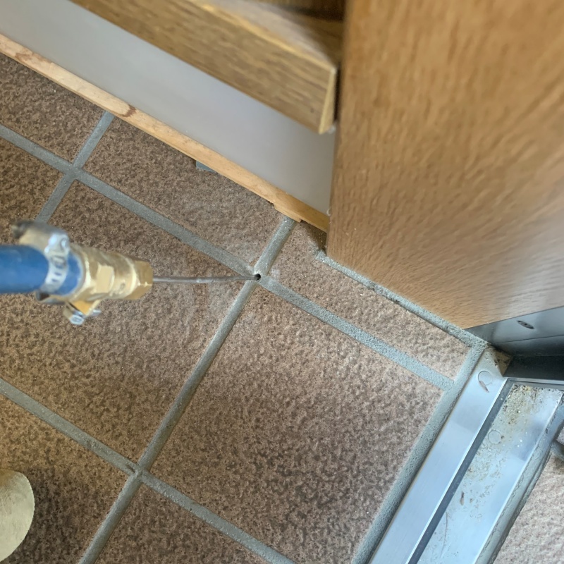 玄関の床にシロアリ駆除剤を注入する様子
