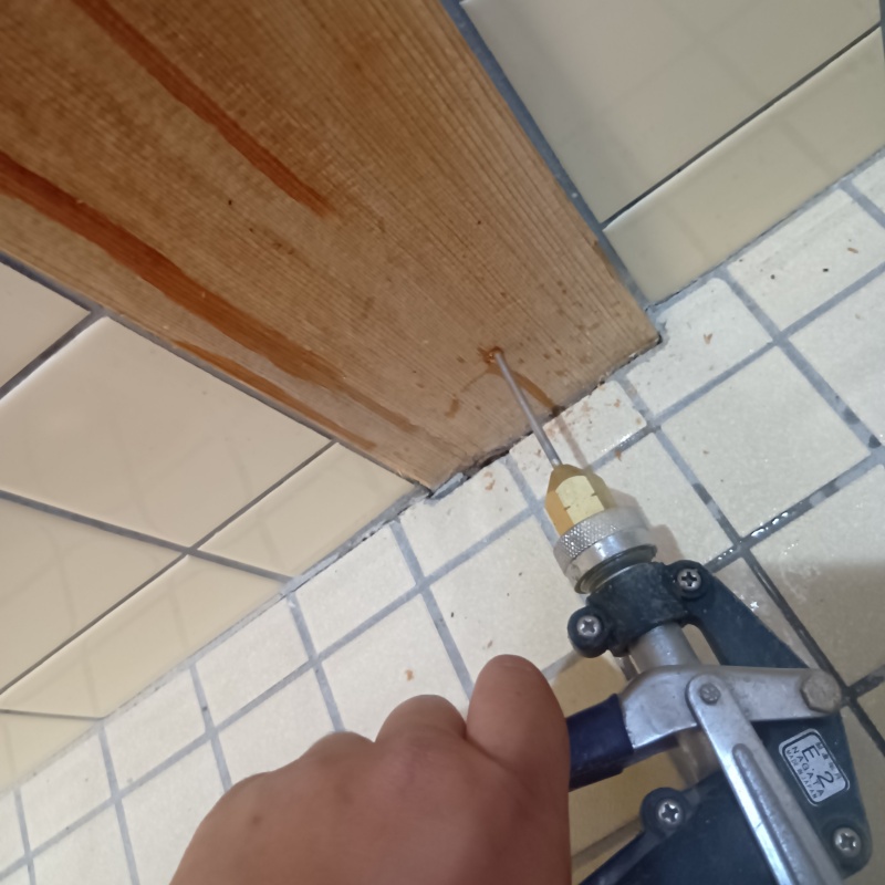 トイレの壁にシロアリ駆除剤を注入する様子