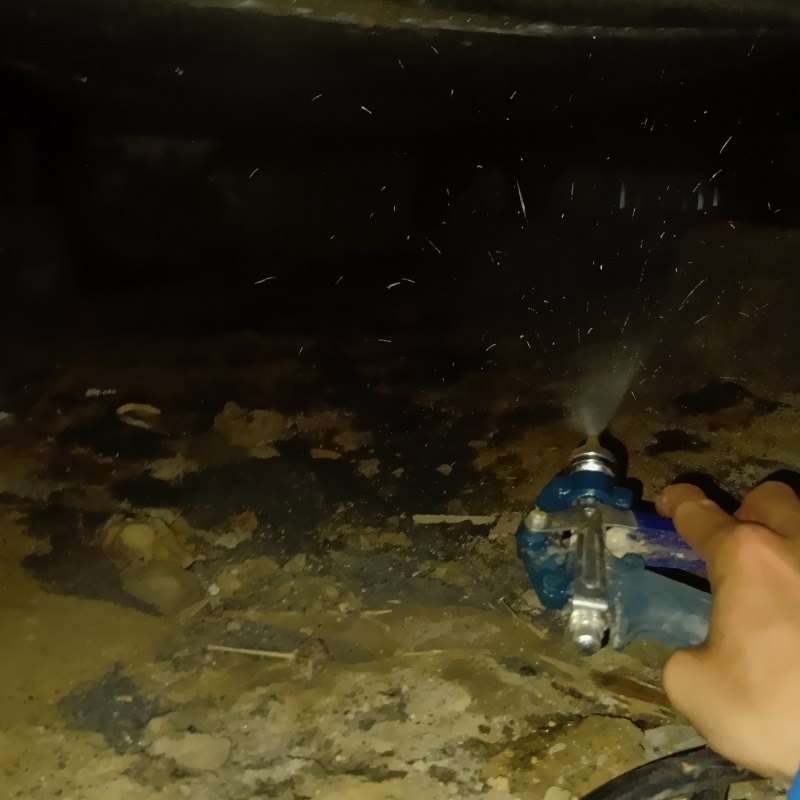 床下の土壌にシロアリ駆除剤を散布する様子