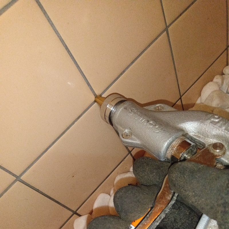 トイレの壁にシロアリ駆除剤を注入する様子